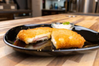 Fried Cheese with Ham cut in half showing melted cheese and ham, plated with a creamy dip.