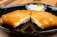 Fried Cheese with Ham cut in half showing melted cheese and ham, served with a creamy dip.
