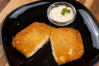 Fried Cheese with Ham, breaded and fried, cut in half showing melted cheese and ham, with a creamy dip.
