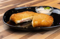Fried Cheese with Ham, breaded and fried, sliced open to show melted cheese and ham, served with a creamy dip.