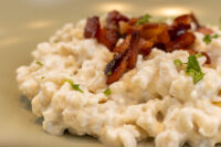 Close-up of Halušky with Bryndza Cheese Substitution topped with crisped bacon and herbs
