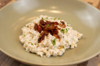Bowl of Halušky with Bryndza Cheese Substitution topped with crispy bacon and chopped herbs