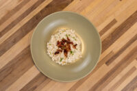 Bowl of Halušky with Bryndza Cheese Substitution topped with crispy bits and herbs on a green plate.