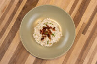 Halušky with Bryndza Cheese Substitution in a green bowl, topped with crispy bacon and herbs.