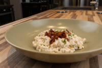 Halušky with Bryndza Cheese Substitution in a green bowl, topped with crispy onions and herbs.