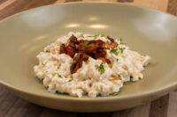 Bowl of Halušky with Bryndza Cheese Substitution topped with crispy bacon and herbs.