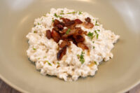 Bowl of Halušky with Bryndza Cheese Substitution topped with crispy bacon and fresh herbs.