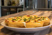 Fried Langos flatbread on a white plate topped with sour cream, cheese, red sauce, and chives