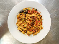 White bowl of Lo Mein with Chicken with noodles, chicken pieces, red peppers, and dark mushrooms