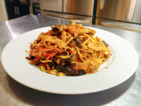 Plate of Lo Mein with Chicken showing noodles, chicken, mushrooms, carrot and pepper strips.