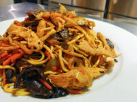 Plate of Lo Mein with Chicken piled with noodles, chicken, carrots, onions and dark wood ear mushrooms.