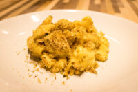 Close-up of Mac & Cheese with creamy sauce and golden herb breadcrumb topping on a white plate