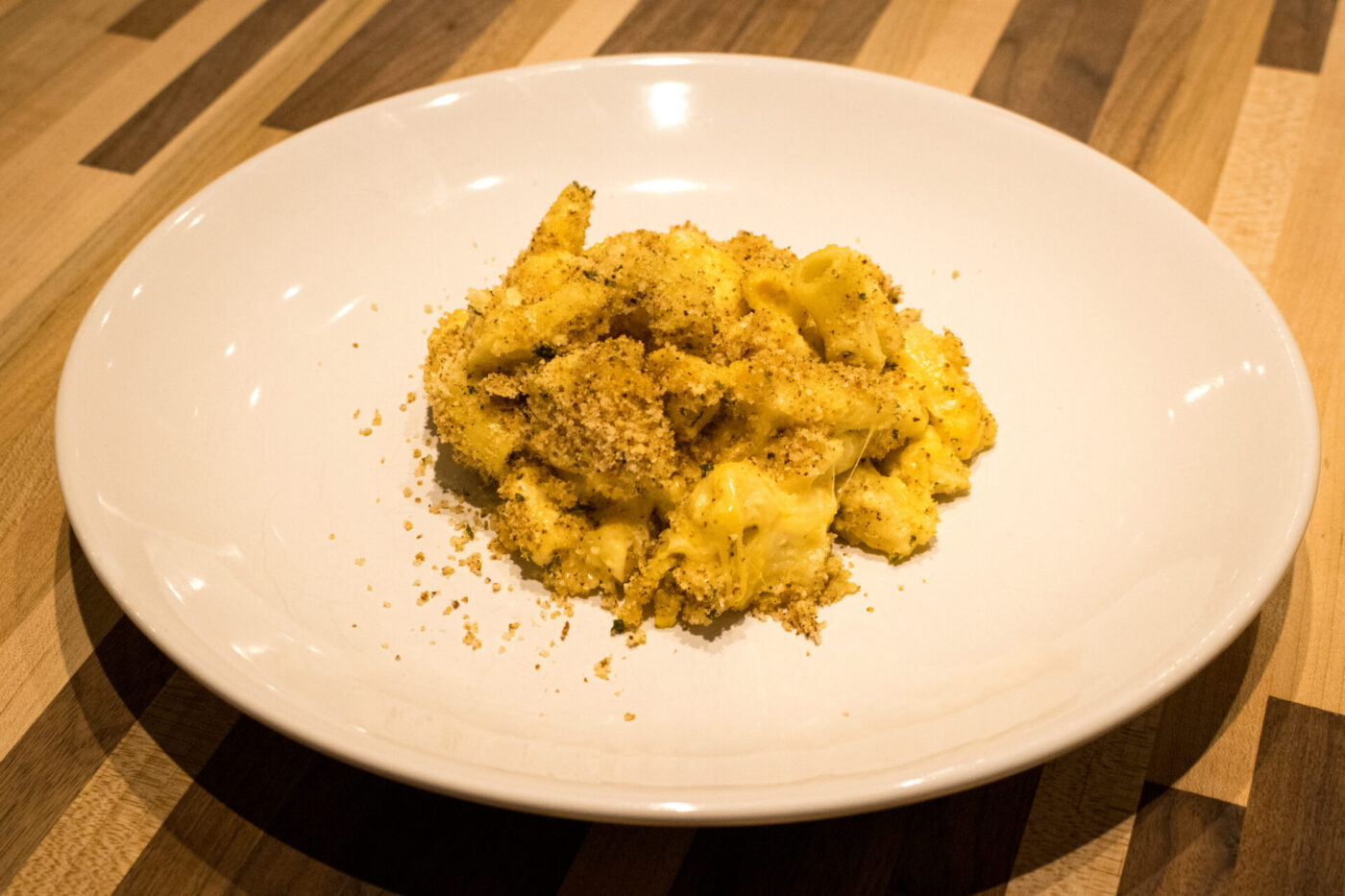 A plate of Mac & Cheese with creamy pasta topped in golden herb breadcrumbs.
