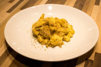 A plate of Mac & Cheese with creamy pasta topped in golden herb breadcrumbs.