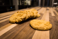 Peanut Butter Cookies with crosshatch fork marks piled on a striped wooden countertop