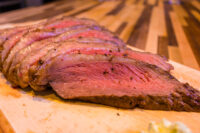 Sliced Beef Picanha in Salt Crust fanned out on a wooden cutting board, pink center visible.