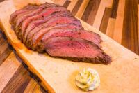 Sliced Beef Picanha in Salt Crust fanned on a wooden board with a swirl of herb butter