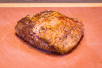 Whole roasted Beef Picanha in Salt Crust with a browned, seasoned crust resting on a scratched cutting board.