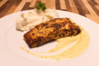 Seared Salmon in Mustard Sauce with dark grill marks, plated beside a scoop of mashed potato topped with a parsley sprig.