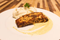 Seared Salmon in Mustard Sauce fillet on mashed potatoes with pale cream sauce, on a white plate.