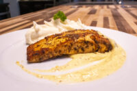 Seared Salmon in Mustard Sauce fillet on mashed potatoes with creamy sauce and parsley garnish.