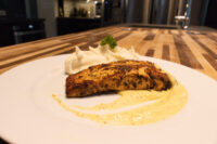 Salmon in Mustard Sauce fillet on a white plate, seared dark and glossy, resting in a pale creamy sauce beside a swirl of mashed potatoes.