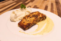 Seared Salmon in Mustard Sauce fillet with mashed potatoes, parsley, and a pale mustard cream sauce on a white plate.