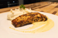 Seared Salmon in Mustard Sauce fillet with mashed potato and parsley on a white plate