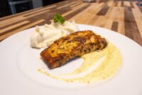 Seared Salmon in Mustard Sauce fillet on a pool of cream sauce, beside swirled mashed potatoes.