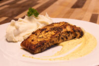 Seared Salmon in Mustard Sauce fillet on mashed potatoes, drizzled with pale mustard cream sauce.