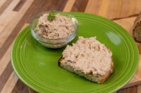 Bowl of Sardines Dip or Spread beside a slice of toast spread with the same mixture on a green plate