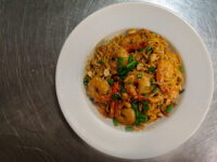 Overhead shot of Thai Noodles with Shrimp topped with scallions, peanuts, and sesame seeds in a white bowl.