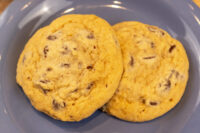 Two golden Chocolate Chip Cookies with visible chocolate chunks resting on a blue plate.