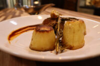 Plated Filet Mignon with Demi-Glace Sauce: seared meat, two fondant potatoes, rosemary, and sauce swirl.