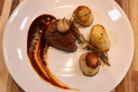 Seared Filet Mignon with Demi-Glace Sauce, fondant potato halves, and rosemary sprig on a white plate