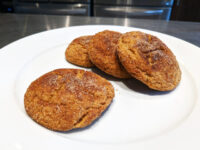 Four Gingersnap Cookies with cracked, sugar-crusted tops on a white plate.