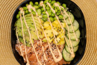 Poke Bowl with Salmon topped with avocado, edamame, mango, cucumber, sesame seeds and spicy mayo drizzle