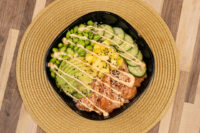 Poke Bowl with Salmon topped with avocado, mango, cucumber, edamame, sesame seeds and creamy drizzle.