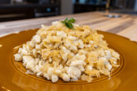 A mound of Halušky with Sauerkraut, white dumplings mixed with golden sauerkraut strands on a brown plate.