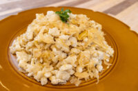 Plate of Halušky with Sauerkraut, crumbled potato dumplings tossed with golden sauerkraut strands, parsley on top.