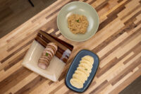 Sliced pork, a bowl of sauerkraut, and dumpling rounds for Pork-Sauerkraut-Dumpling (Vepřo-knedlo-zelo) on a wood table