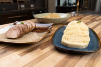 Sliced roast pork, sliced dumpling rounds, and a bowl of sauerkraut for Pork-Sauerkraut-Dumpling (Vepřo-knedlo-zelo).