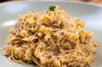 Close-up of Sauerkraut (Kysane Zelí) with caraway seeds and parsley on a mint-green plate.