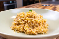 Shredded Sauerkraut (Kysané Zelí) in a creamy glaze, garnished with parsley, on a white plate.