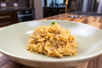 A pale green bowl holds golden, shredded Sauerkraut (Kysane Zelí) topped with chopped herb.