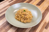 A pale green bowl of Sauerkraut (Kysane Zelí), shredded and golden, topped with a small herb garnish on a wooden table.