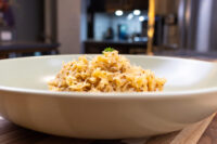 White bowl of shredded Sauerkraut (Kysane Zelí) topped with a light garnish and herb sprig on a wooden table.