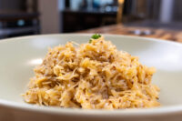 White bowl heaped with shredded Sauerkraut (Kysane Zelí), browned edges, topped with a herb sprig.
