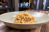 Shredded Sauerkraut (Kysane Zelí) with red spice flecks and herb garnish in a pale bowl on wood.
