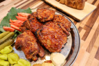 Czech BBQ – Honey Pork Ribs glazed pieces on a platter with tomato, kale, pickles, and pepperoncini